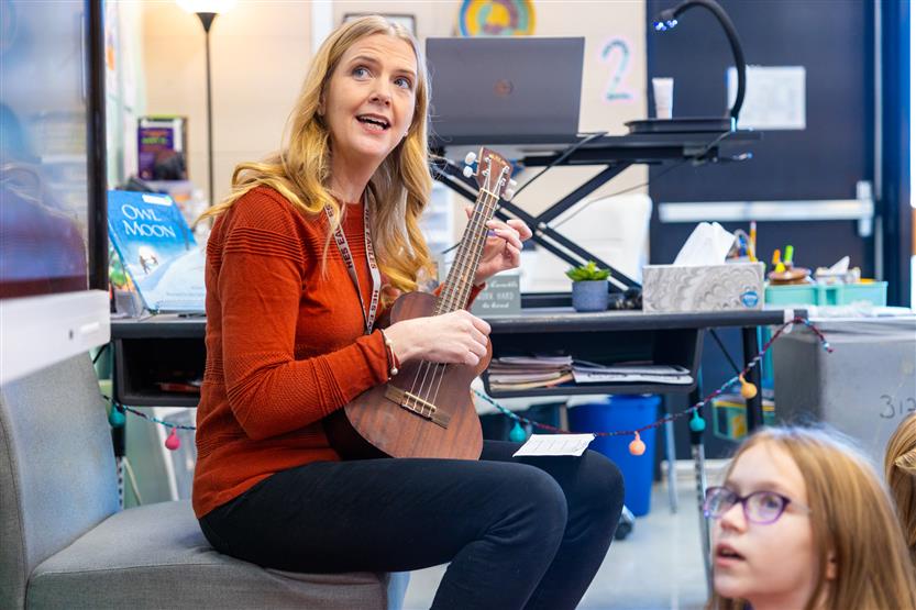 A teacher plays a ukulele for her students